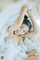 A woman laying in a bathtub covered in white foam.