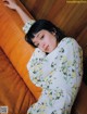 A woman laying on top of a brown couch.