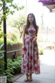 A woman in a floral dress poses for a picture.