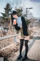 A woman standing on a sidewalk holding a cup of coffee.