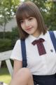 A young woman in a school uniform sitting on a bench.