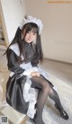 A woman in a maid outfit sitting on a chair.