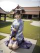 A woman in a purple kimono sitting on the ground.