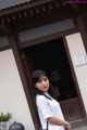 A woman standing in front of a building with a black bag.