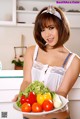 A woman holding a plate of vegetables in a kitchen.