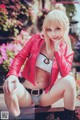 A woman in a red leather jacket sitting on a bench.