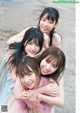 A group of young women hugging each other on a beach.