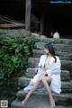 A woman in a white robe sitting on some steps.